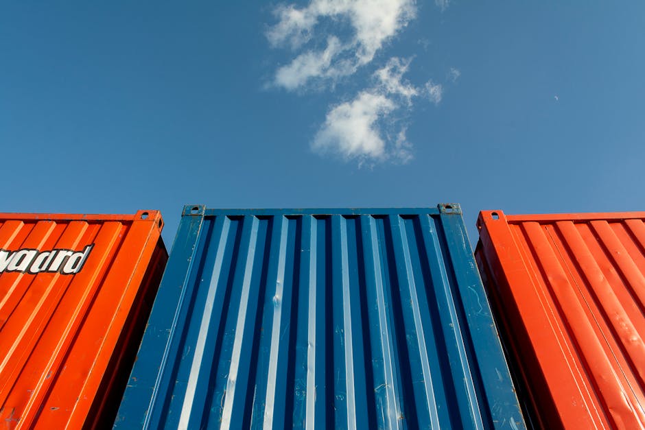 Vibrant red and blue shipping containers under a clear sky, perfect for industrial themes.