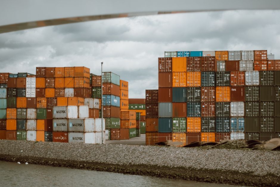 Colorful shipping containers stacked in Rotterdam harbor, under overcast skies.